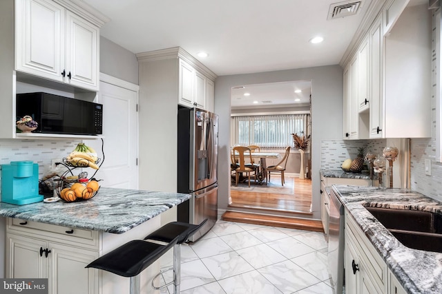 kitchen featuring light stone counters, visible vents, marble finish floor, and appliances with stainless steel finishes