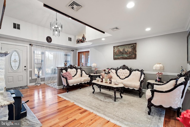 living room featuring crown molding, wood finished floors, visible vents, and a chandelier