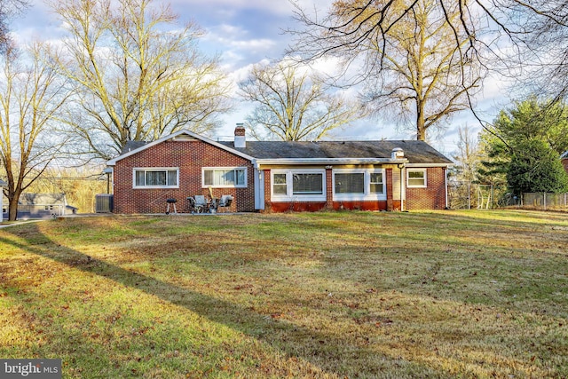 view of front of house with a front yard, fence, brick siding, and a chimney