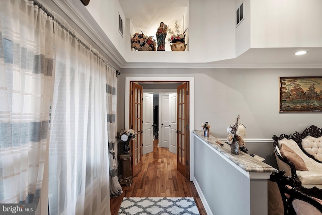 hall featuring visible vents, crown molding, and wood finished floors