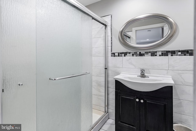 bathroom featuring vanity, a shower stall, and tile walls