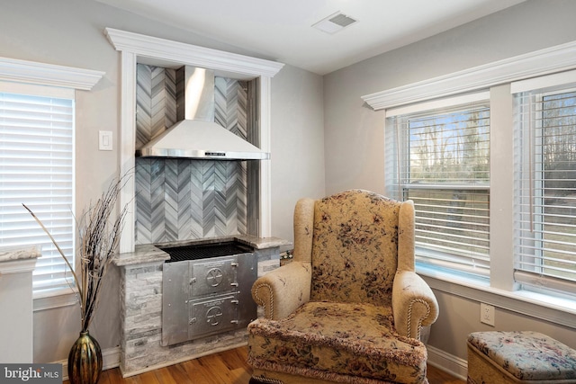 living area featuring visible vents, plenty of natural light, baseboards, and wood finished floors