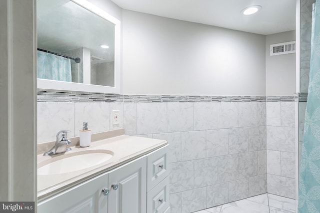 bathroom with visible vents, a shower with curtain, tile walls, and vanity