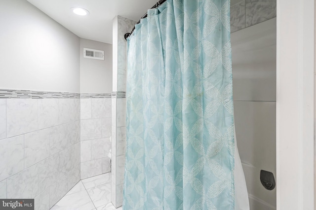 full bath featuring a shower with shower curtain, visible vents, and tile walls