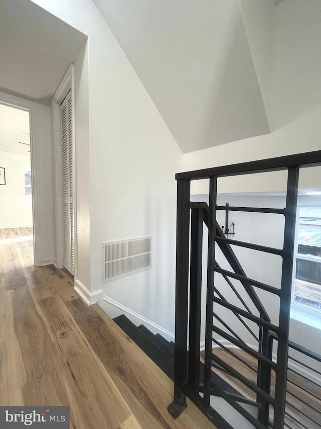 stairs featuring vaulted ceiling, wood finished floors, visible vents, and baseboards