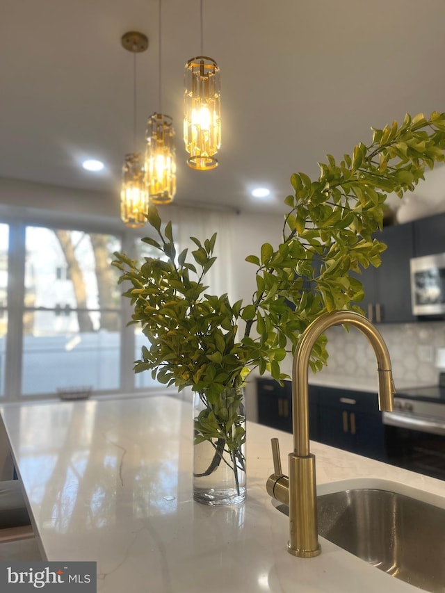 room details featuring light stone counters, stainless steel microwave, decorative light fixtures, backsplash, and a chandelier