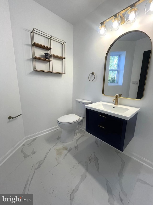 half bathroom with baseboards, toilet, marble finish floor, and vanity