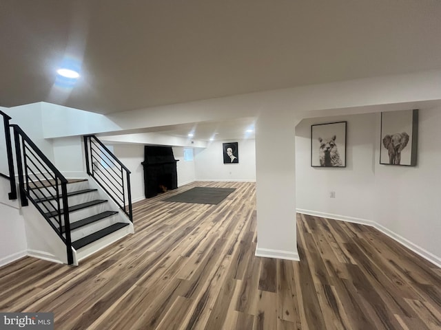 finished below grade area with a fireplace, stairs, baseboards, and wood finished floors