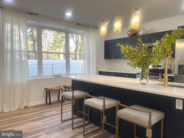 interior space featuring decorative light fixtures, decorative backsplash, a breakfast bar, and light wood-style floors