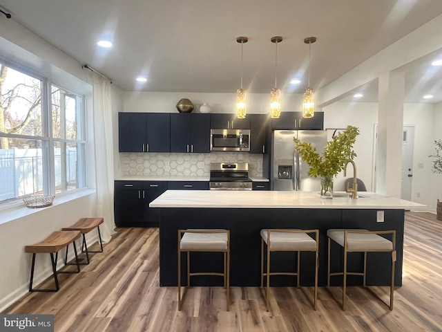 kitchen with appliances with stainless steel finishes, light countertops, a kitchen breakfast bar, and dark cabinets