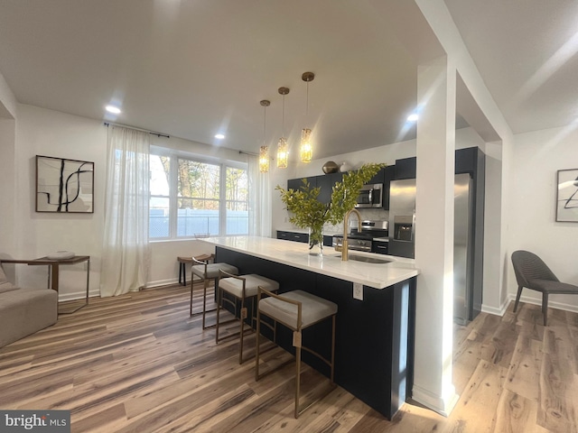 kitchen with a sink, stainless steel appliances, light wood finished floors, and light countertops