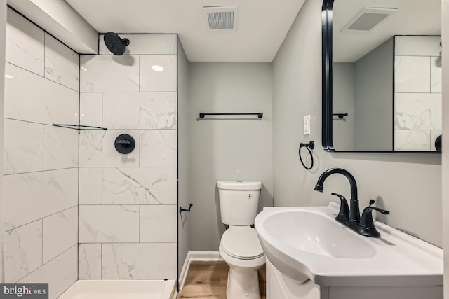 bathroom with a sink, visible vents, tiled shower, and toilet