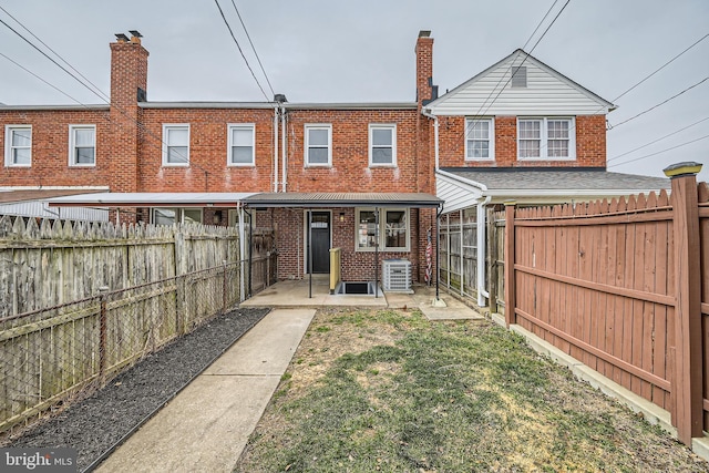 back of property featuring a yard, a fenced backyard, brick siding, and a chimney