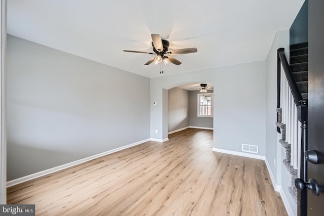 interior space featuring visible vents, baseboards, wood finished floors, arched walkways, and a ceiling fan