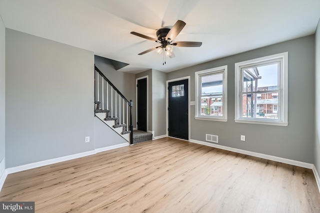 foyer entrance featuring stairway, a ceiling fan, wood finished floors, baseboards, and visible vents