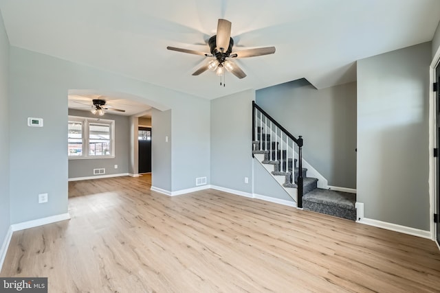 unfurnished living room with stairway, wood finished floors, baseboards, visible vents, and ceiling fan