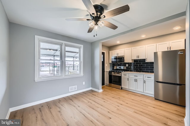 kitchen with white cabinetry, tasteful backsplash, visible vents, and appliances with stainless steel finishes