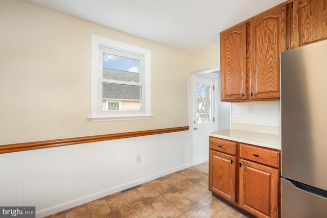 kitchen with plenty of natural light, brown cabinets, light countertops, and freestanding refrigerator