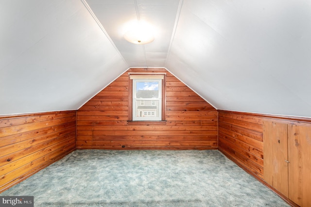 additional living space featuring wood walls, carpet, and vaulted ceiling