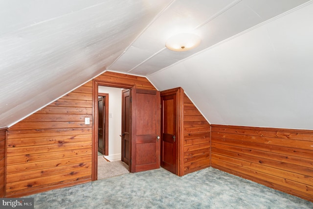 additional living space with carpet floors, wood walls, and vaulted ceiling