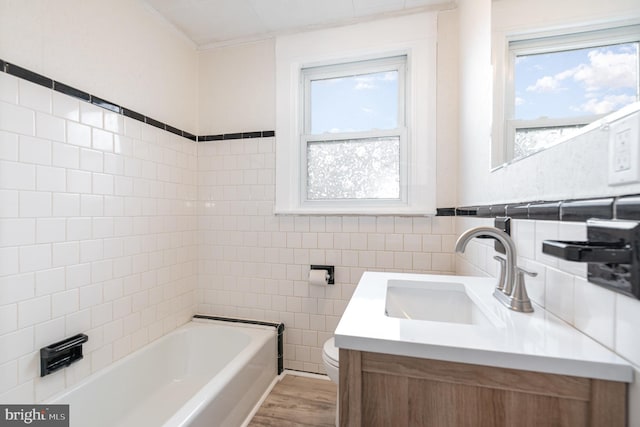 full bathroom with tile walls, toilet, a healthy amount of sunlight, and a tub to relax in