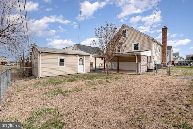 back of house featuring a patio, a fenced backyard, and a gate