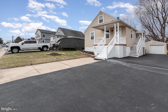 bungalow-style home with driveway, a porch, stairway, an outdoor structure, and a garage