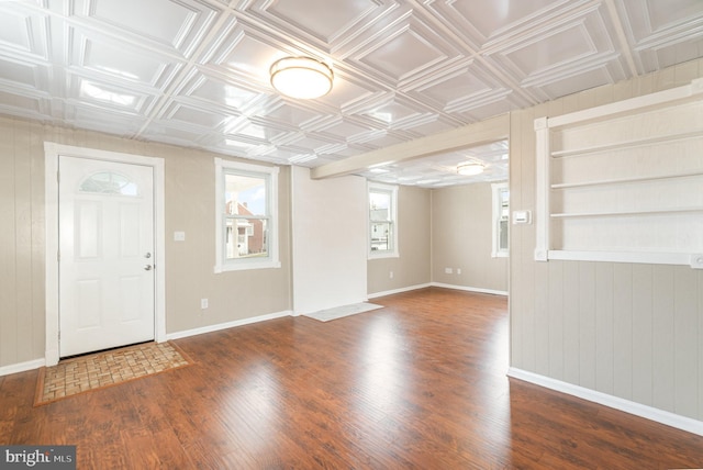 entryway with wood finished floors, baseboards, an ornate ceiling, and wood walls