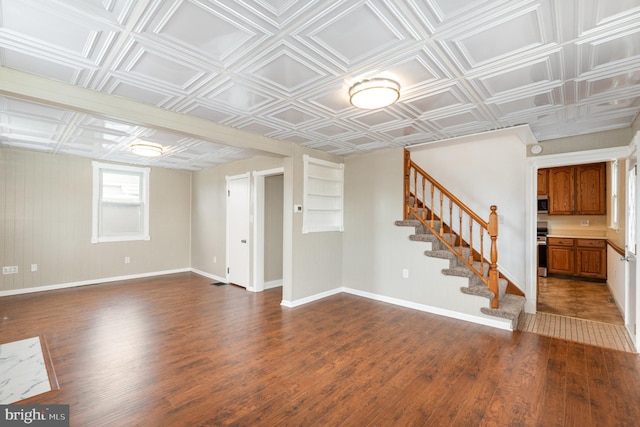 basement with dark wood finished floors, stairway, an ornate ceiling, and baseboards