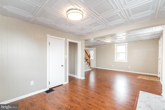 empty room featuring visible vents, an ornate ceiling, and wood finished floors