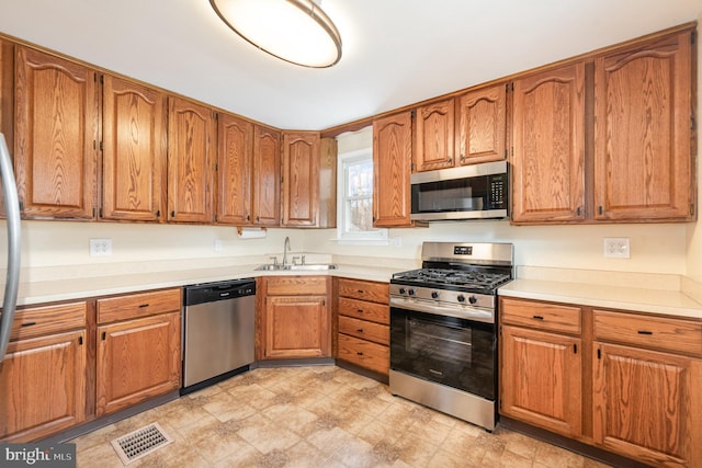 kitchen with a sink, brown cabinetry, visible vents, and stainless steel appliances