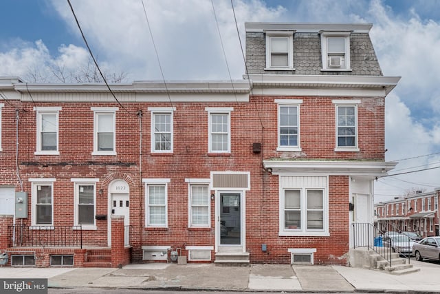 multi unit property featuring brick siding, entry steps, and mansard roof