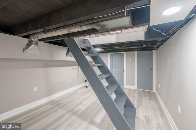 finished basement featuring stairs, wood finished floors, and baseboards