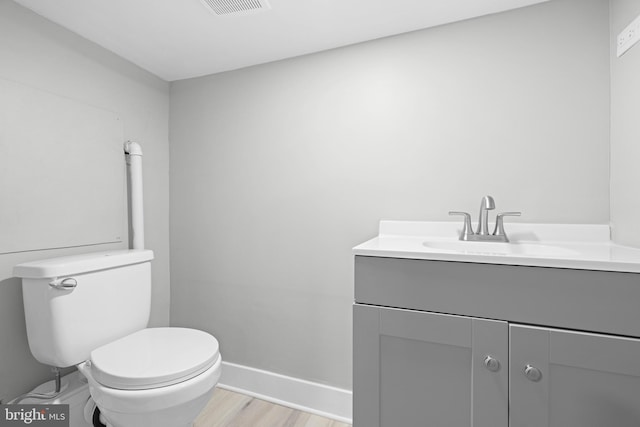 bathroom featuring vanity, wood finished floors, visible vents, baseboards, and toilet