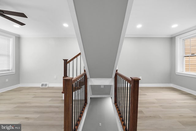 hallway featuring visible vents, an upstairs landing, a healthy amount of sunlight, and ornamental molding