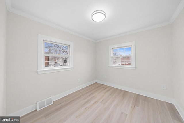 empty room featuring ornamental molding, wood finished floors, visible vents, and baseboards