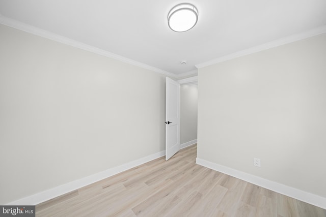 empty room with ornamental molding, baseboards, and light wood-type flooring