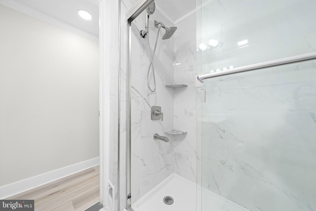 bathroom with crown molding, wood finished floors, baseboards, and a marble finish shower