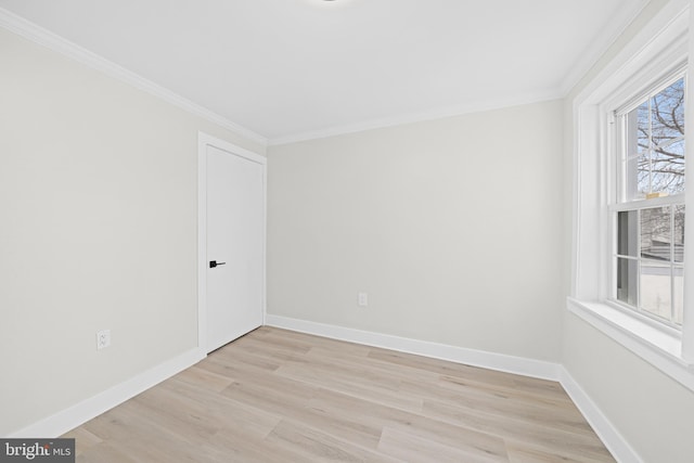 spare room with light wood-type flooring, crown molding, and baseboards