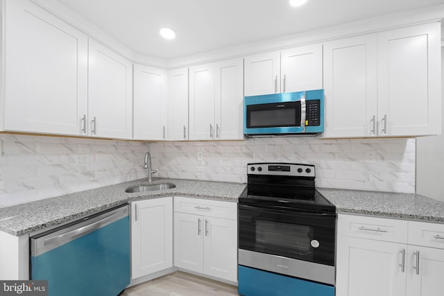 kitchen featuring a sink, light stone counters, tasteful backsplash, stainless steel appliances, and white cabinets