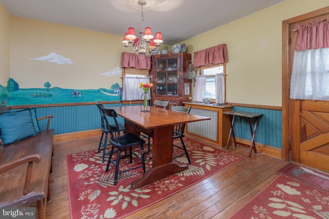 dining room with a wainscoted wall, an inviting chandelier, and hardwood / wood-style floors