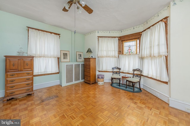 living area with a textured ceiling, baseboards, and a ceiling fan