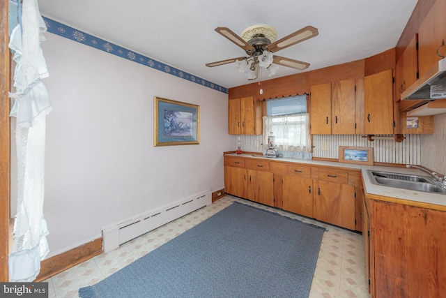 kitchen featuring brown cabinetry, light floors, a baseboard radiator, ceiling fan, and a sink