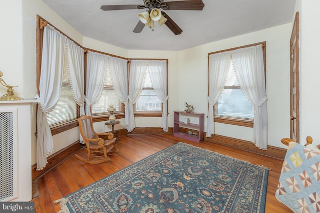 sitting room with ceiling fan, baseboards, plenty of natural light, and wood finished floors