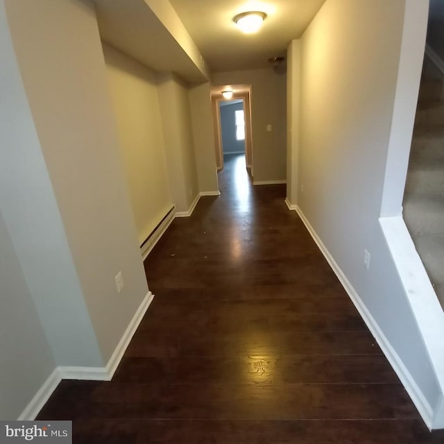 hall featuring a baseboard heating unit, baseboards, and wood finished floors