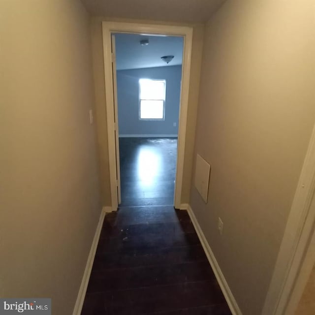 hallway featuring dark wood-type flooring and baseboards