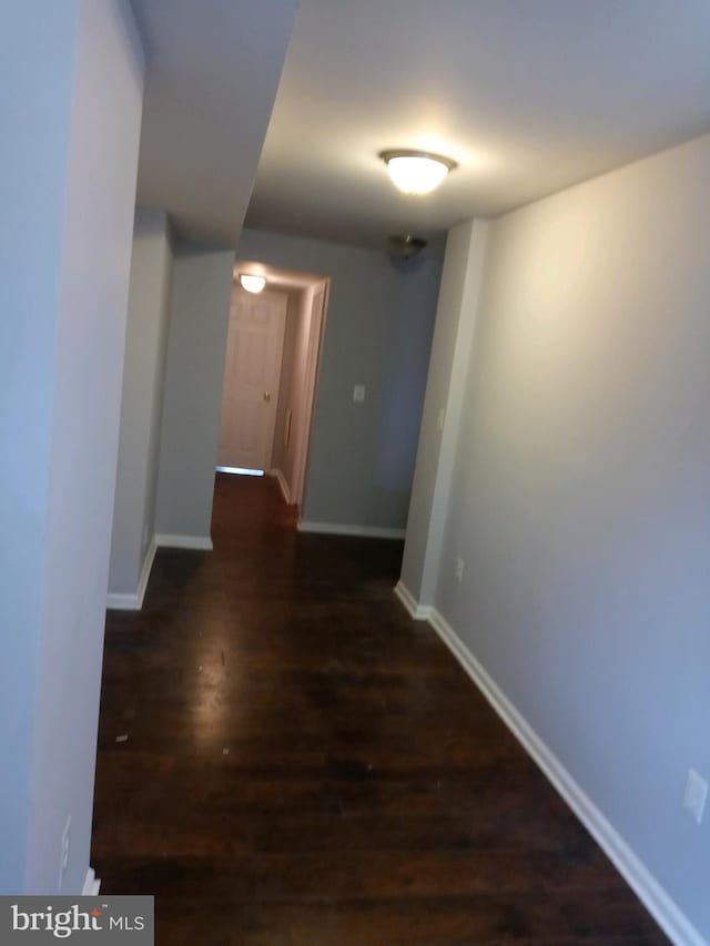 hallway featuring dark wood finished floors and baseboards