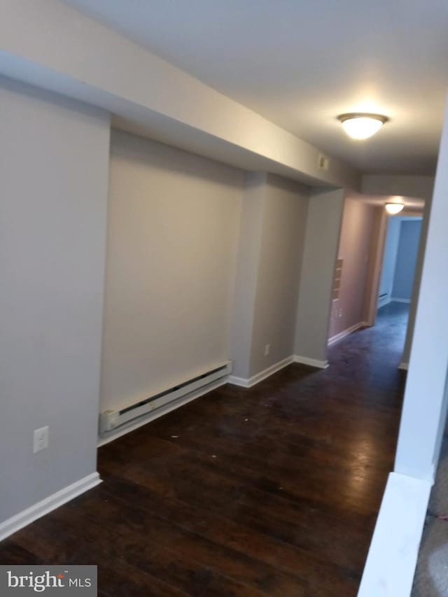 interior space with baseboards, baseboard heating, and wood finished floors