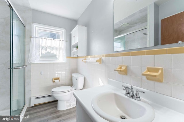 bathroom with a shower stall, wood finished floors, and a baseboard radiator