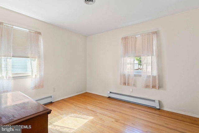 empty room with baseboards, baseboard heating, and wood finished floors